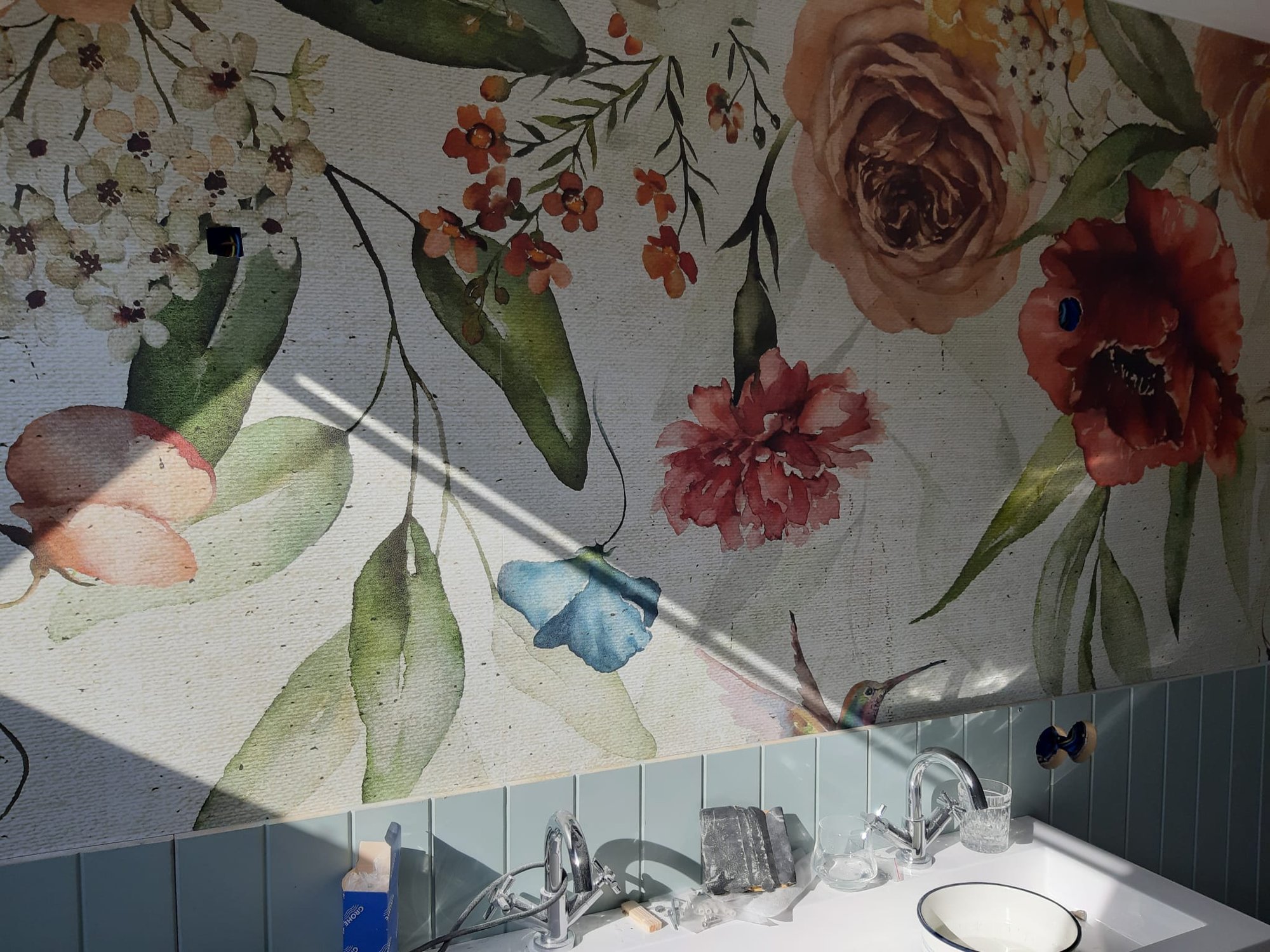 Botanisch bloemenbehang met rozen en papavers boven de wastafel met eucalyptusgroene lambrisering in Hoogezand