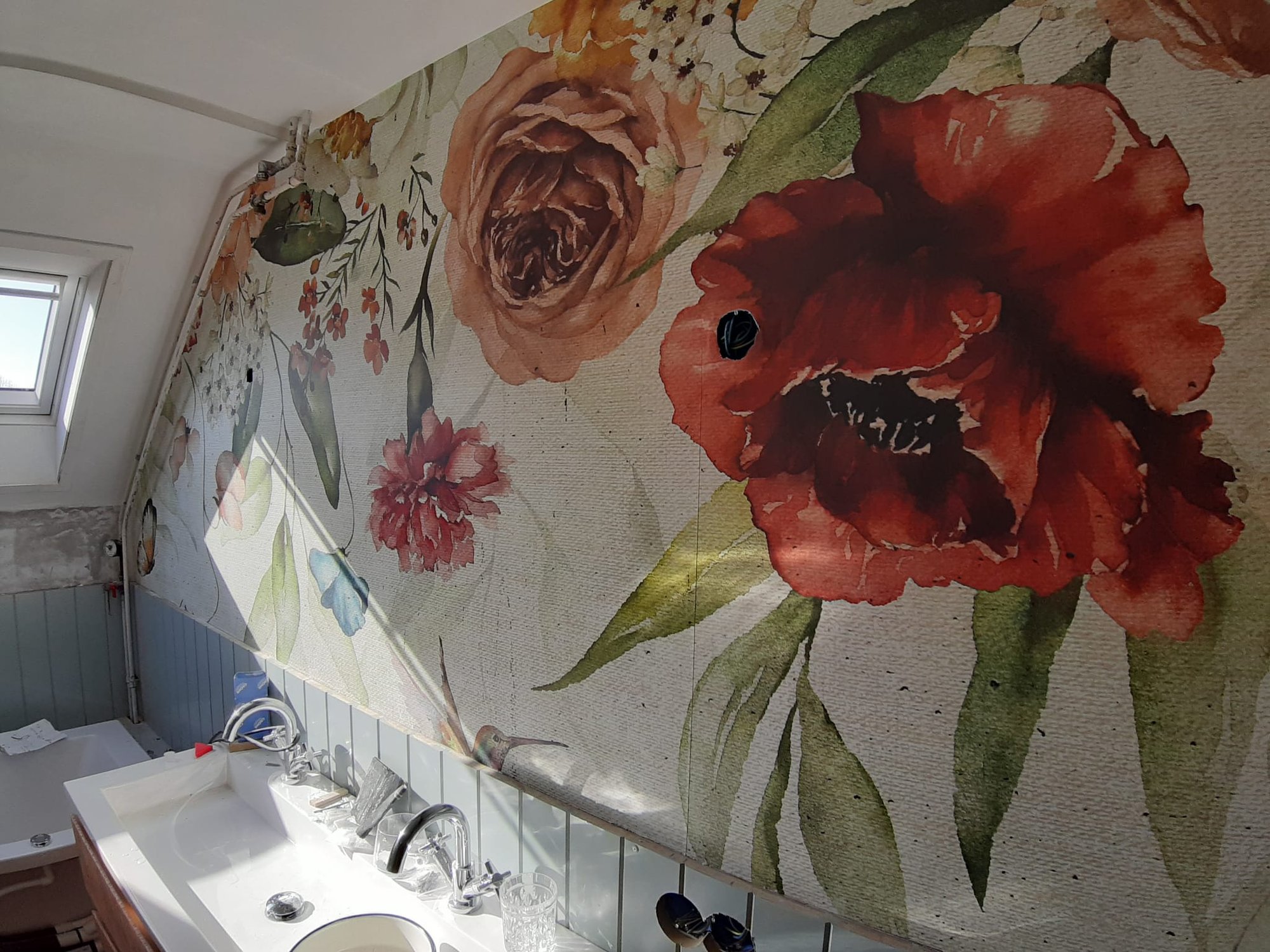 Romantisch bloemenbehang met rozen en papavers boven de wastafel met lambrisering