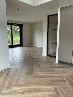 Visgraat tegelvloer in licht eikenlook die doorloopt door de hele open woonruimte met tuindeuren