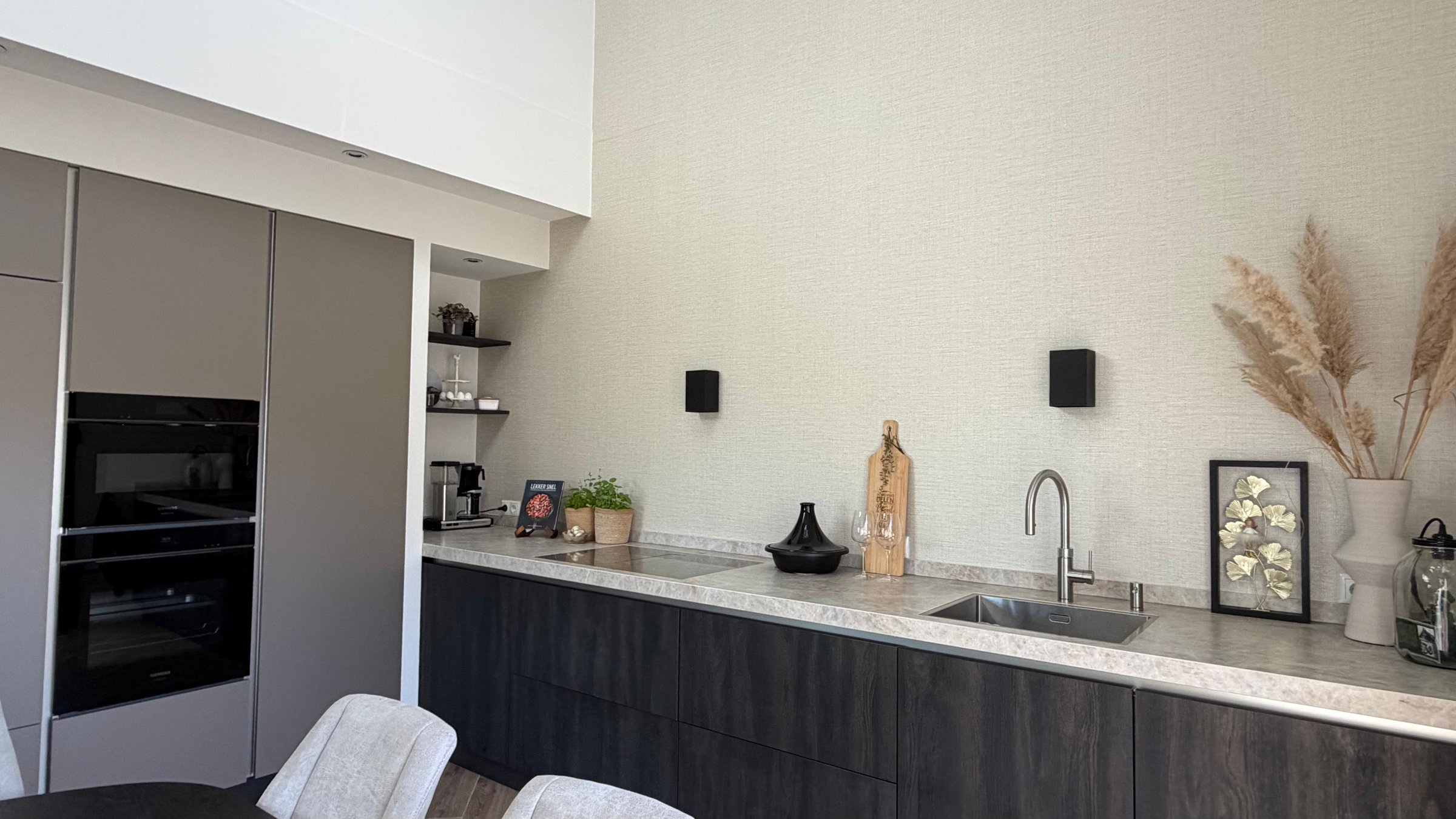Moderne keuken met donkere fronten, licht werkblad en ingebouwde apparatuur in een nieuwbouwwoning in Nooitgedacht