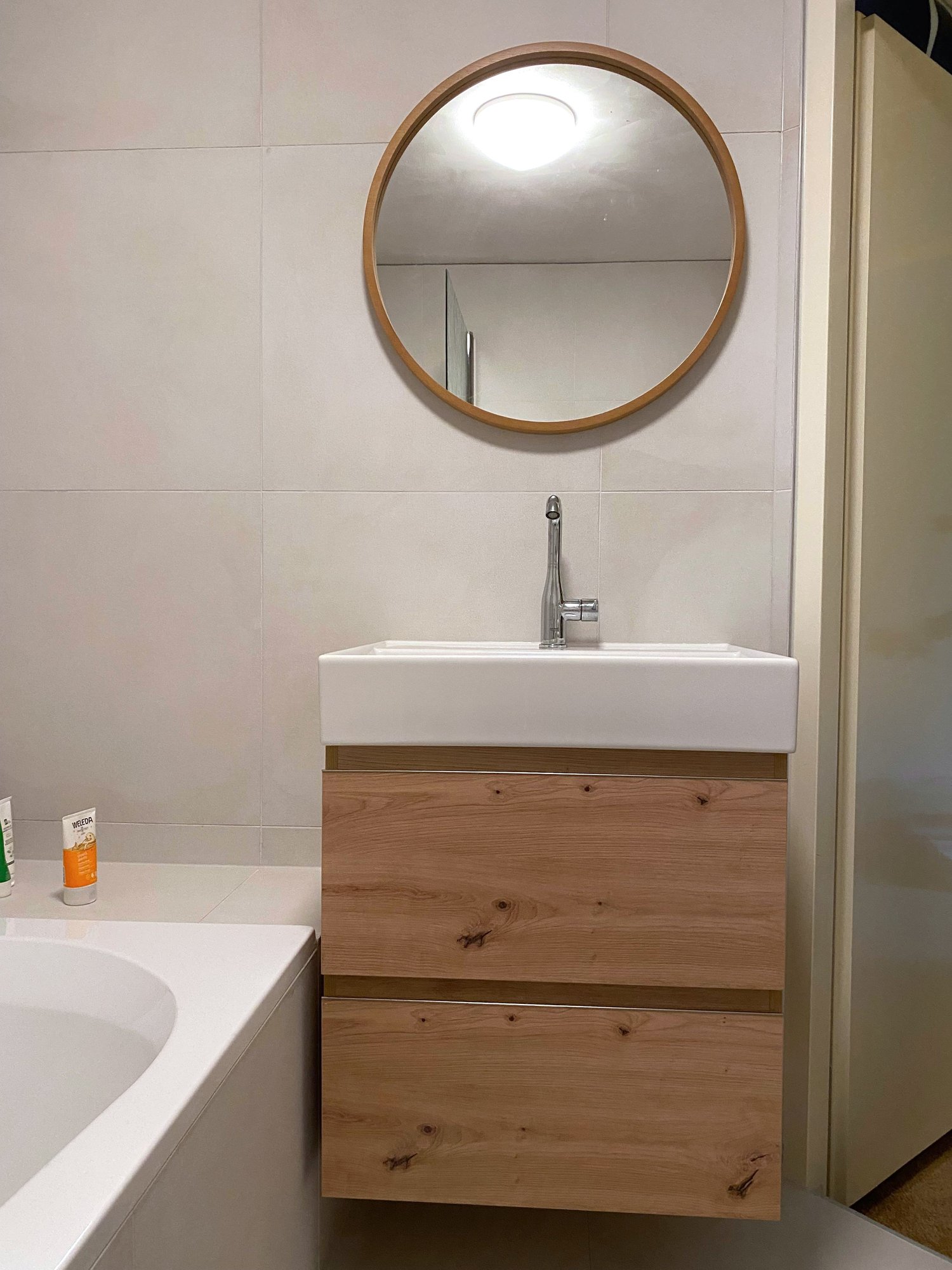 Eikenhouten wastafelmeubel met ronde spiegel in een gerenoveerde badkamer in Assen
