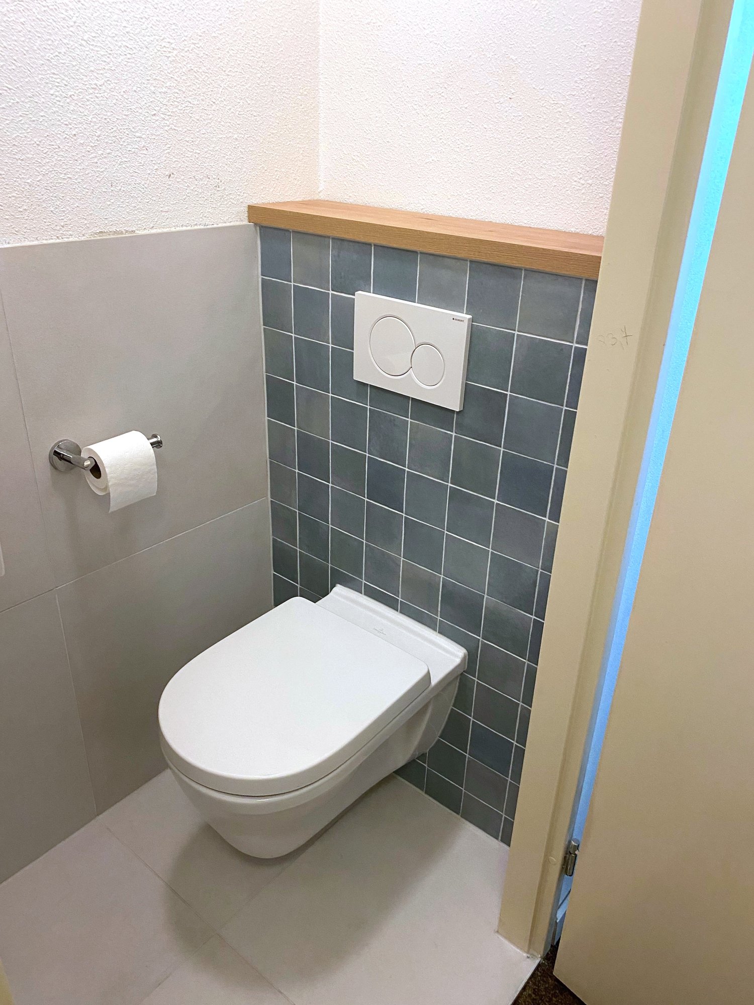 Wandhangend toilet met blauwgrijze tegels en Geberit-bedieningsplaat in Assen Marsdijk